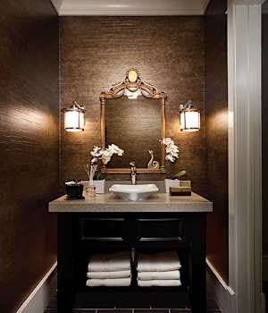 Luxury powder room with black vanity, gold-framed mirror, and rich brown wall finishes