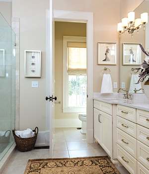Bathroom with cream cabinets, polished hardware, and a large glass-enclosed shower