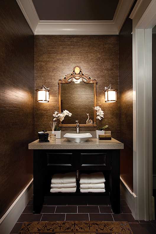 Luxury powder room with black vanity, gold-framed mirror, and rich brown wall finishes