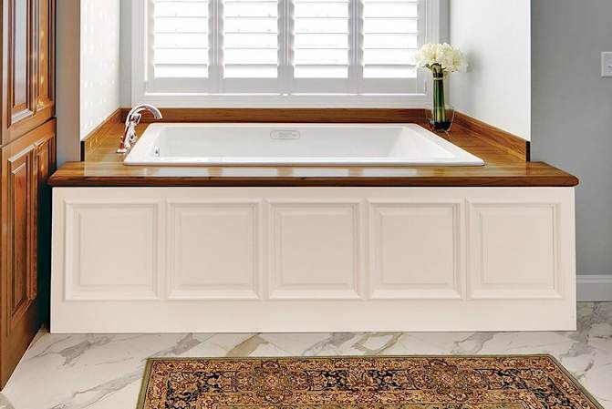 bathtub with white wainscot panel on the bottom and wooden accents