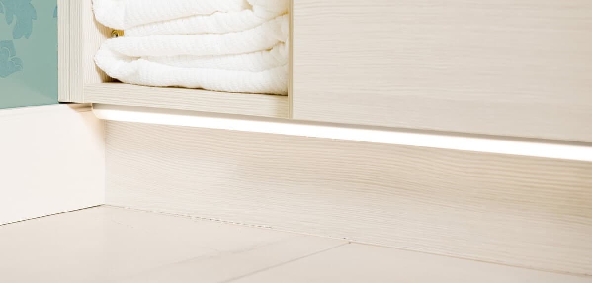 Under cabinetry lighting in bathroom with white cabinetry