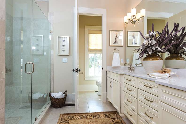 Bathroom with cream cabinets, polished hardware, and a large glass-enclosed shower